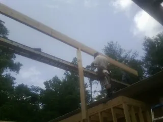 Carpenter setting a ridge beam over a new addition frame — Ice Dam Removal by Roofing Brothers in Annabella