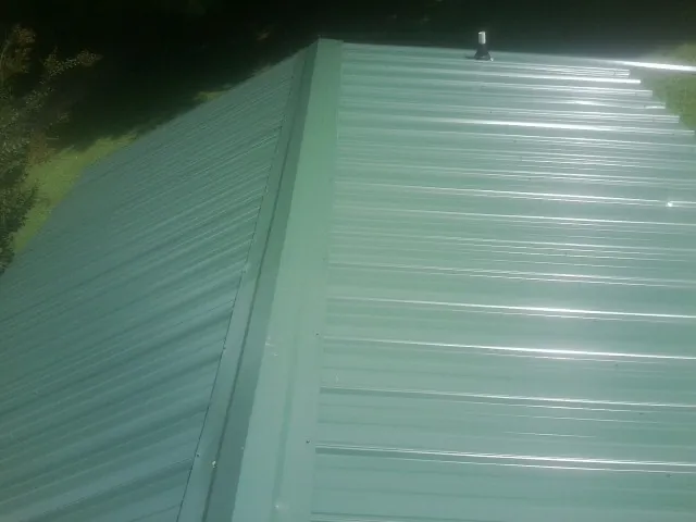 New green metal panels meeting at the ridge of a roof — Flat Roof Repair work by our crew in Annabella