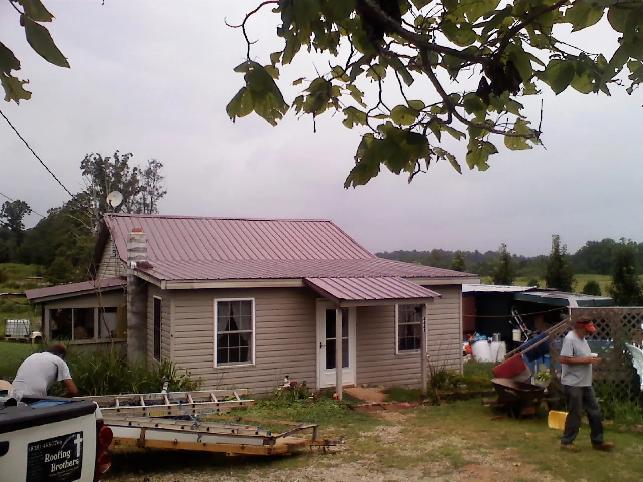 Crew finishing a mauve metal roof on a small farmhouse in Annabella