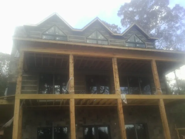 Dormers and porch framing on a large log home under construction — Roof Coating work by our crew in Annabella