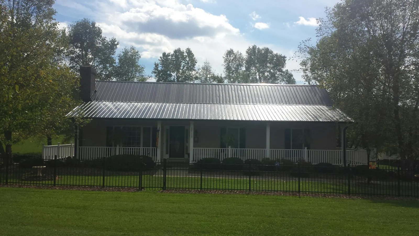 Gray metal roof on a brick ranch with a full width front porch — Gutter Guard Installation work by our crew in Annabella