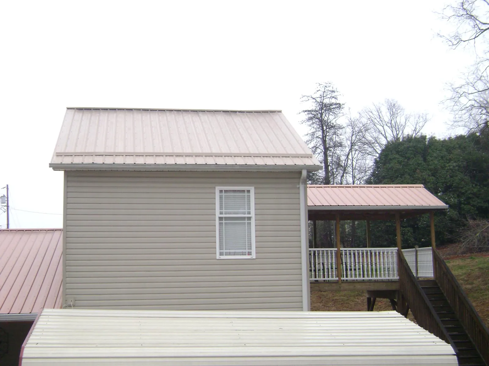 Tan metal roofs on a two story addition and attached porch, from a Roof Replacement job in Annabella