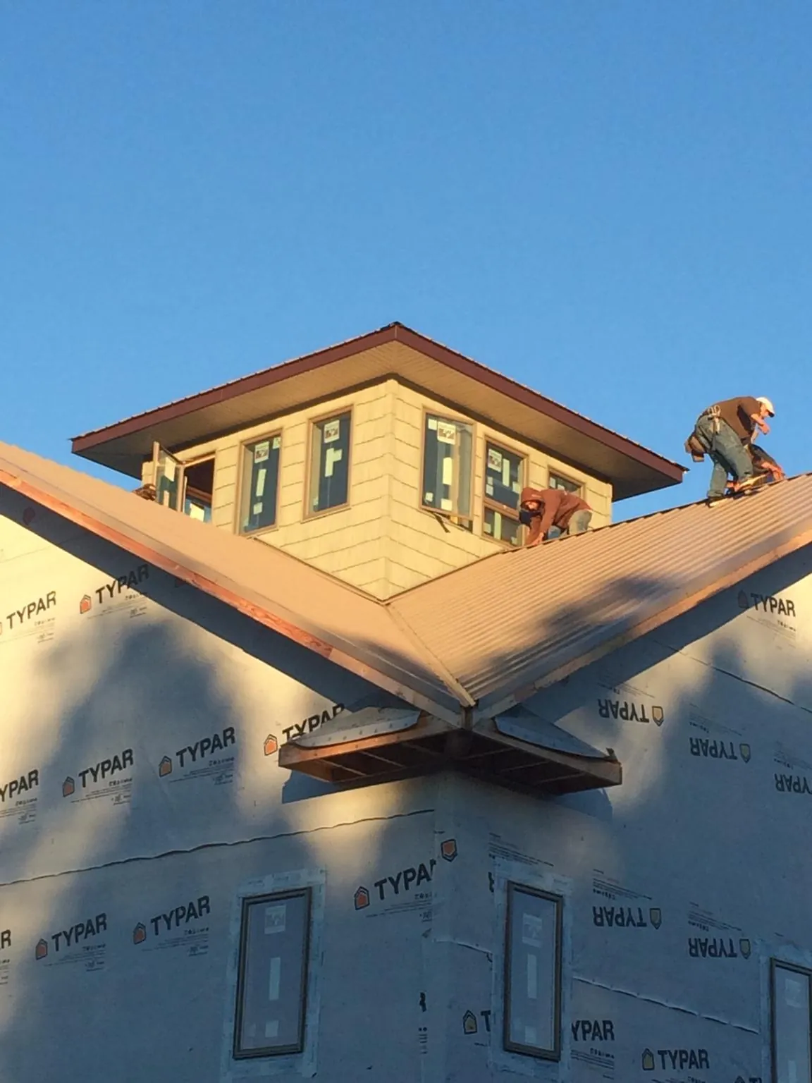 Roofers working around a rooftop cupola on a new metal roof at sunset — Roof Waterproofing in Annabella by Roofing Brothers